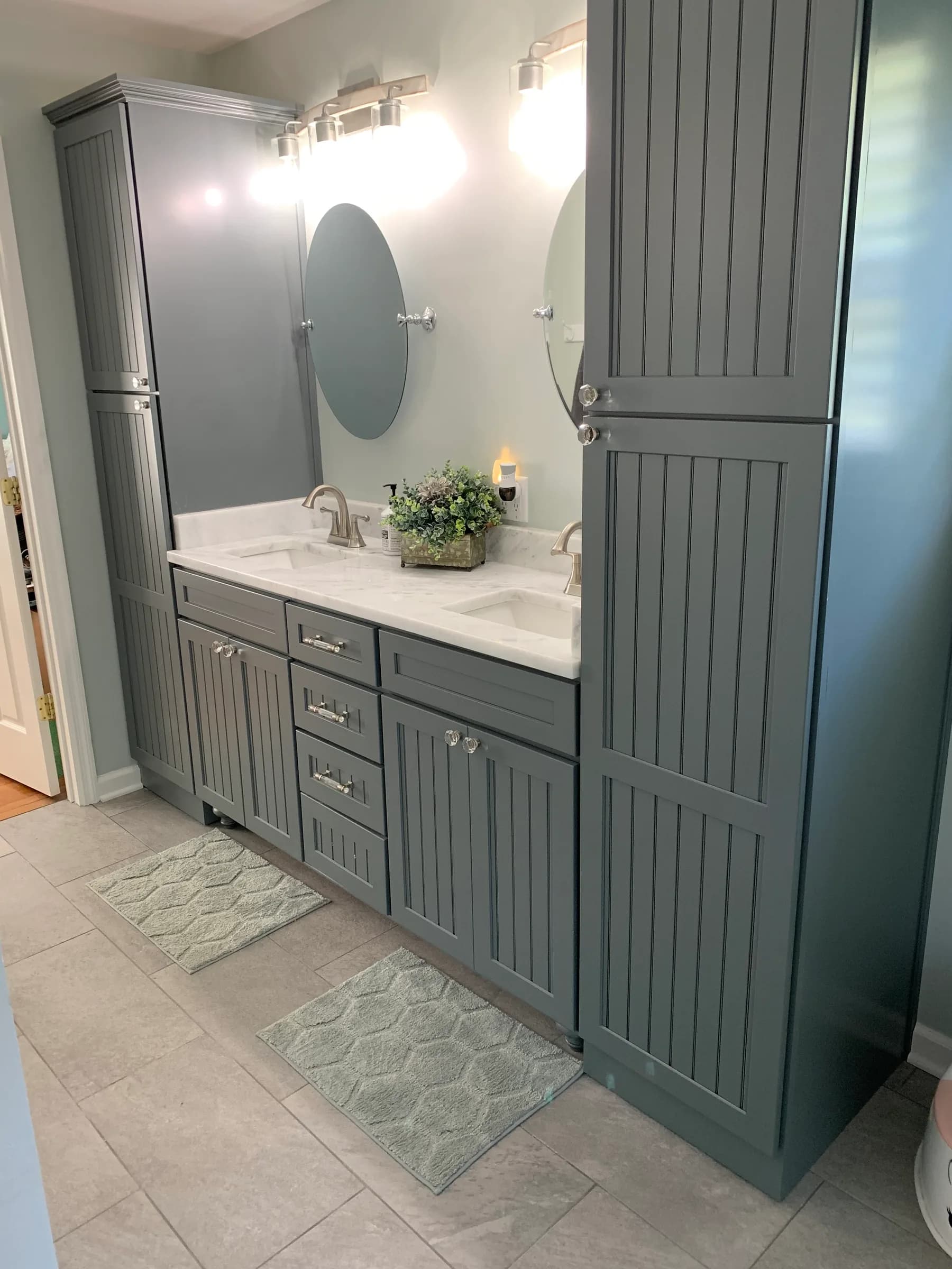 Slate blue double vanity with beadboard doors and a matching tall linen tower