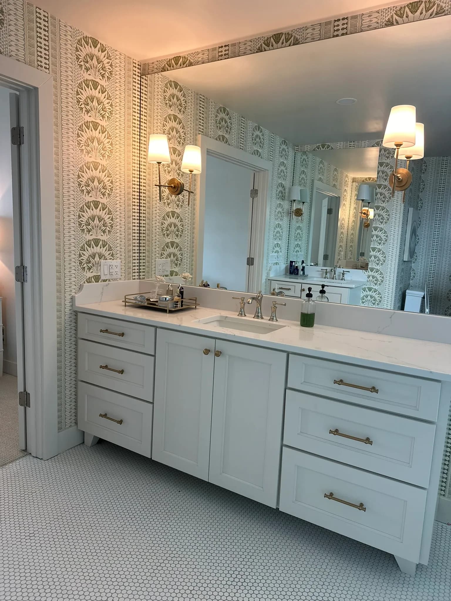 Pale blue bathroom vanity with a marble top, undermount sink, and wall sconces