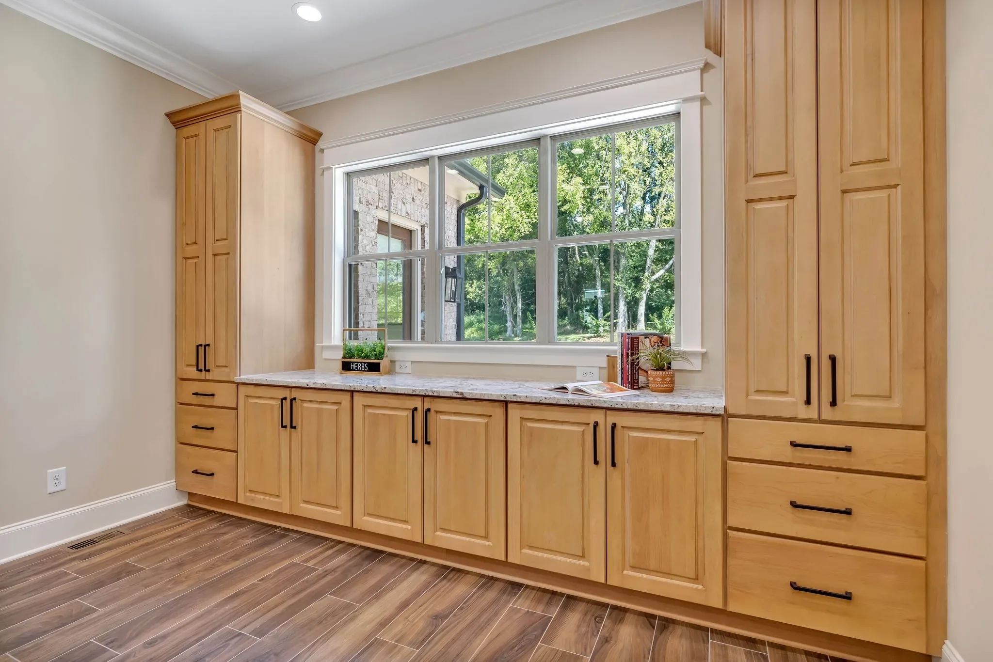 Built-in maple cabinetry wall with a base run beneath the window and tall storage towers either side