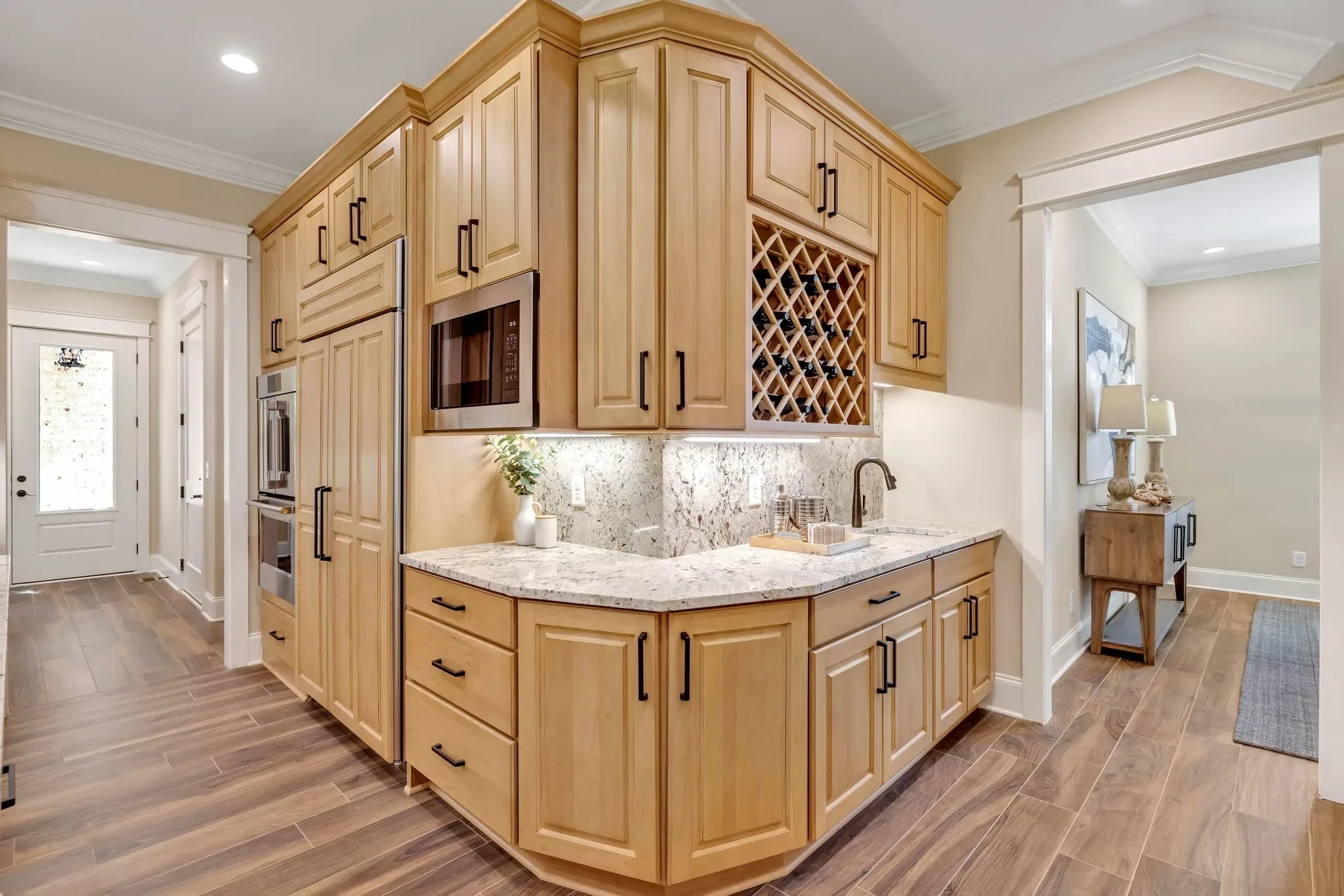 Honey maple kitchen with a wine lattice, built-in microwave, and granite counters