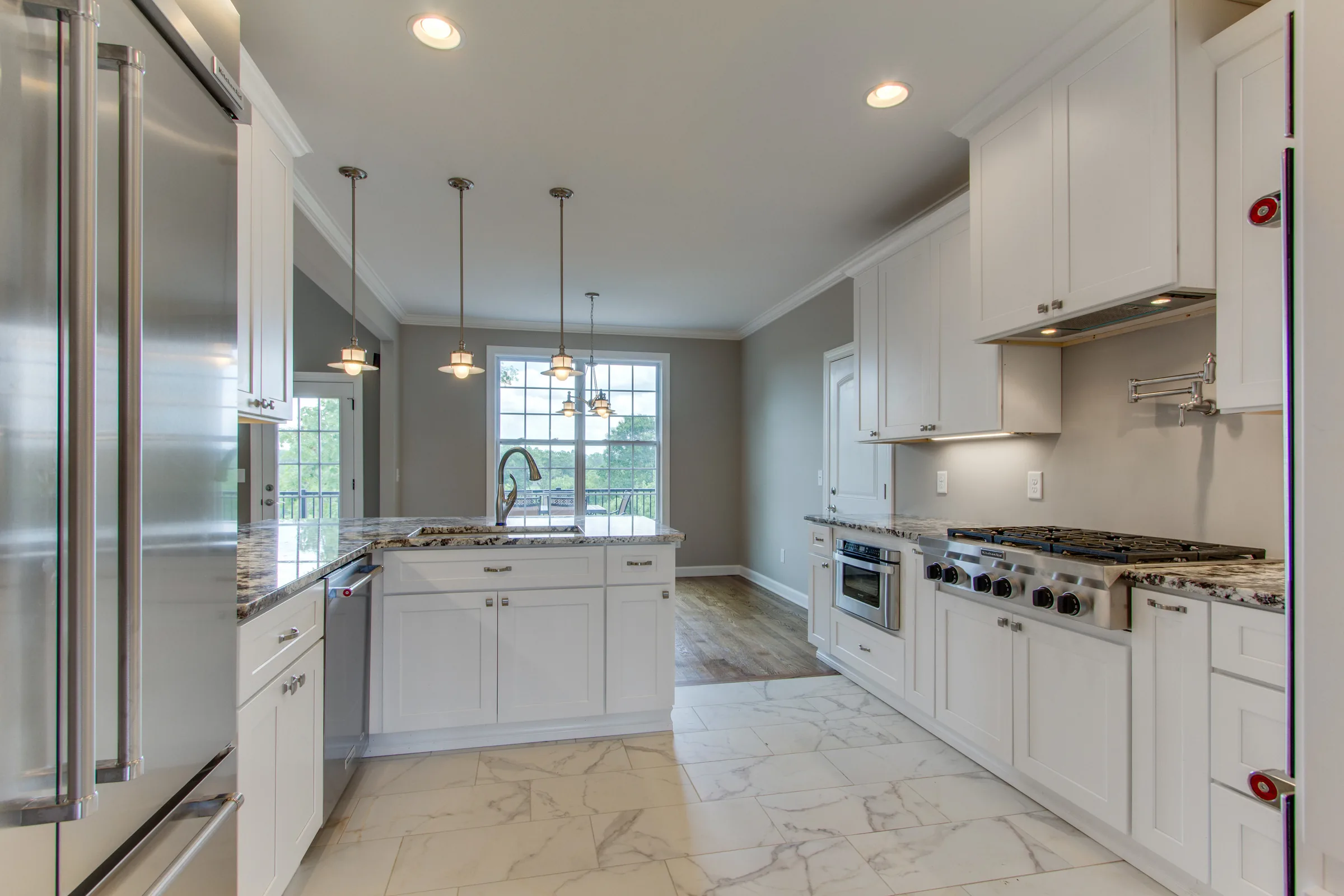 White shaker kitchen with a professional range, marble floor, and a large island