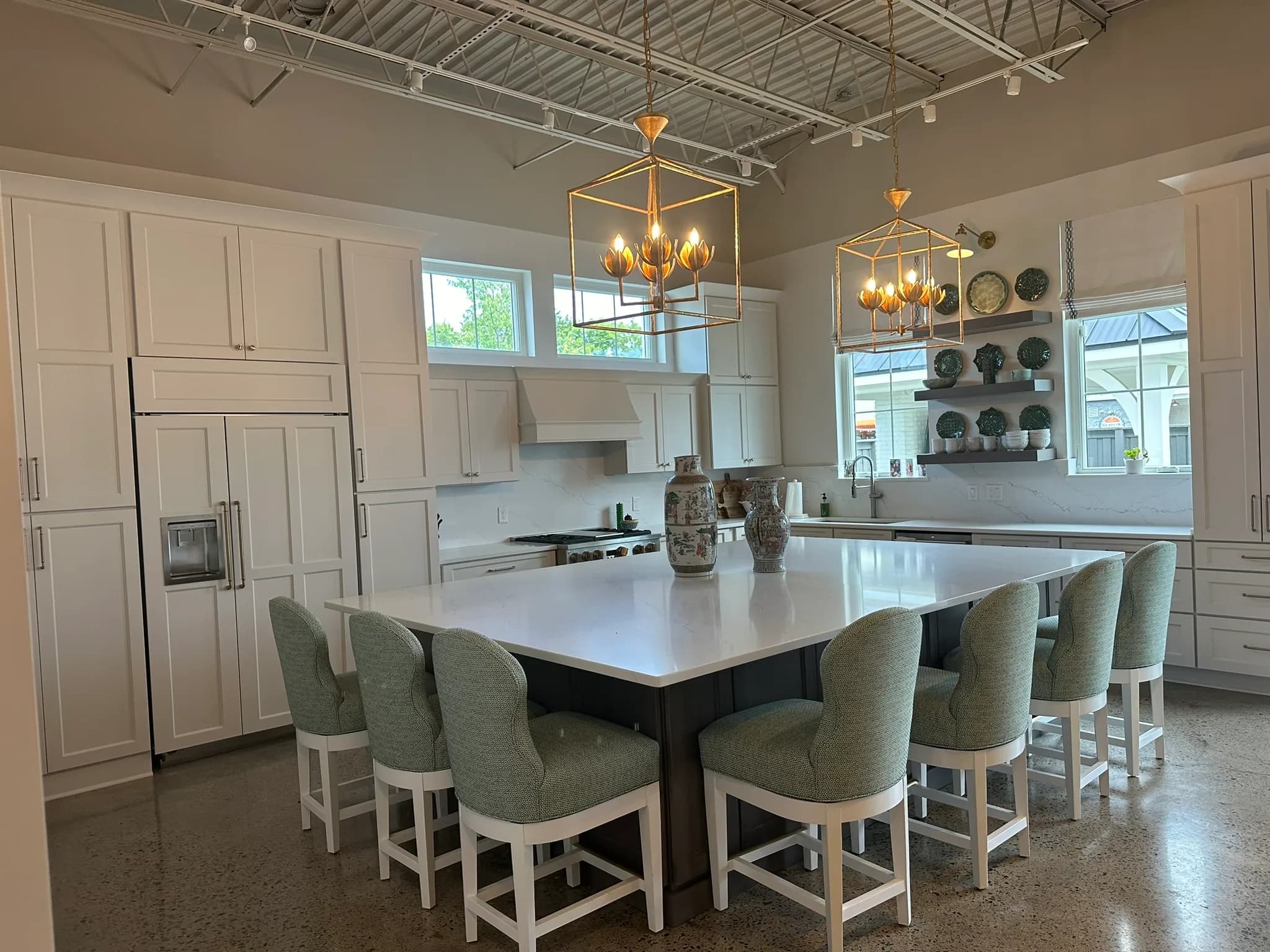 Bella Casa showroom display kitchen with a large island, brass lantern pendants, and open shelving